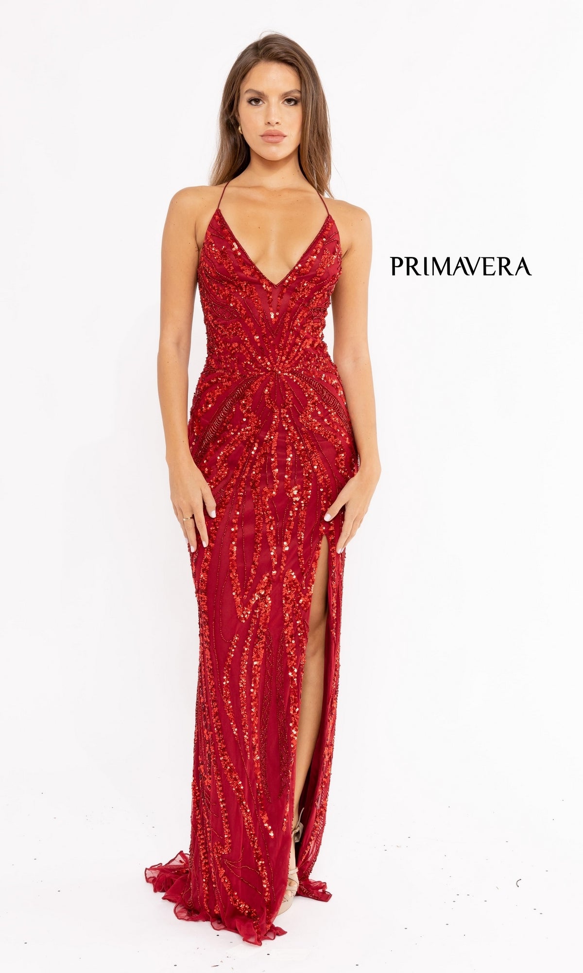 A woman models the Strappy-Back Long Sequin Prom Dress 3958 in deep red with a thigh-high slit, standing against a white background with